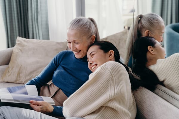 Two women smiling together on a couch