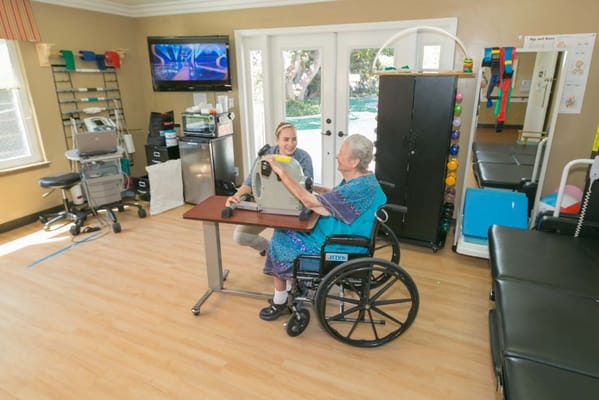 A staff member assisting a resident in a therapy room
