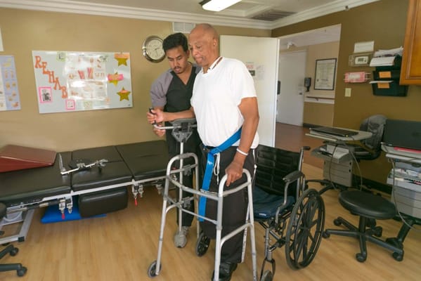 Staff assisting a resident in a therapy room