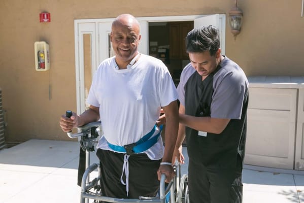 Staff assisting a resident outside with a walker