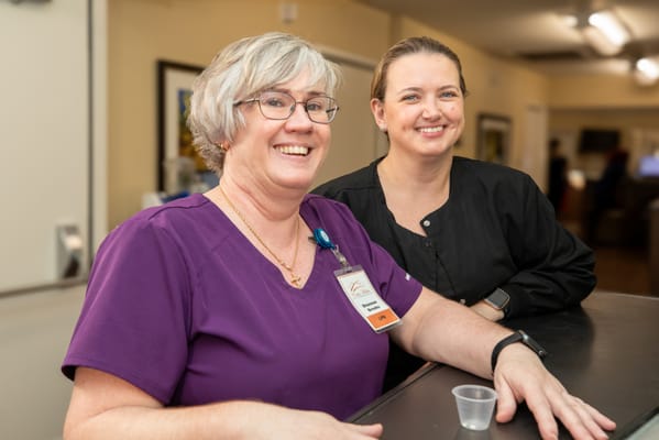 Two staff members smiling at the reception area