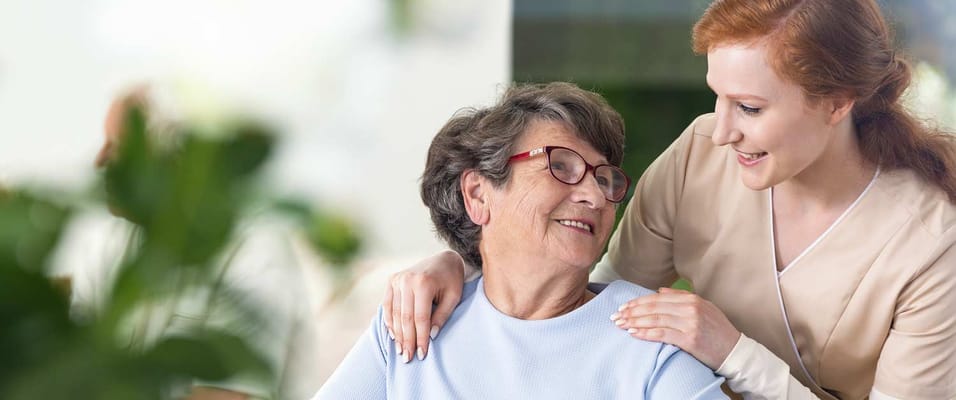 A caregiver smiling with a resident in a bright interior