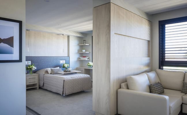 Brightly lit resident room with bed and lounge area