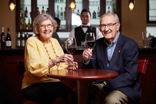 Two residents toasting with glasses in a cozy bar setting