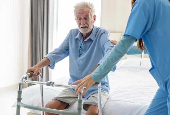 Nurse assisting an elderly man with a walker