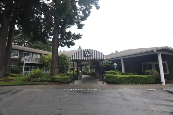 Front view of Weatherly Inn Tacoma entrance with a striped awning.