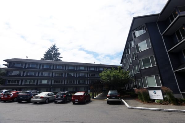 The exterior of The Village Senior Living facility with parking area.