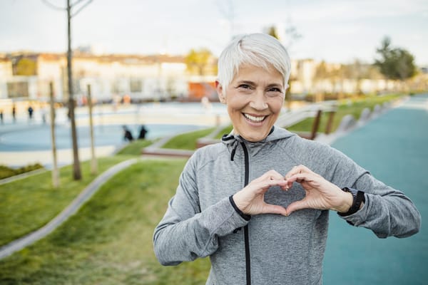 Senior woman making a heart shape with her hands outdoors