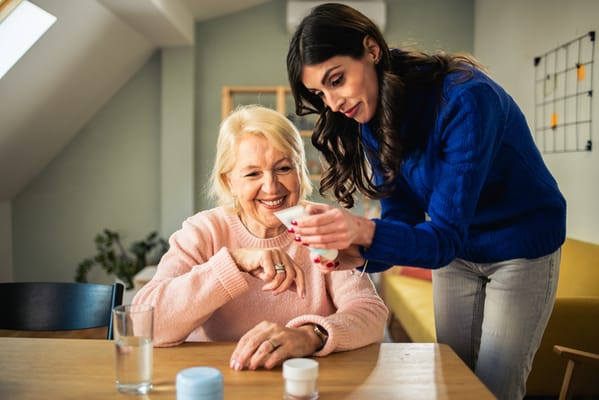 Care staff assisting a smiling resident at a shared table