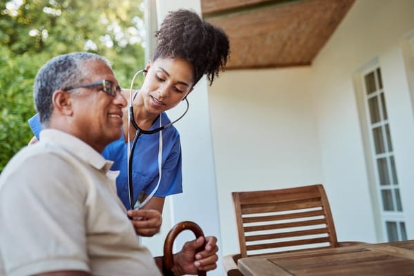 A caregiver using a stethoscope on a resident outdoors