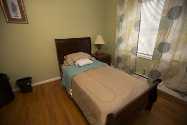 A private bedroom with a single bed and lamp