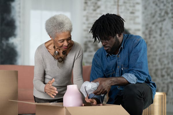 Elderly woman and young man unpacking a box together