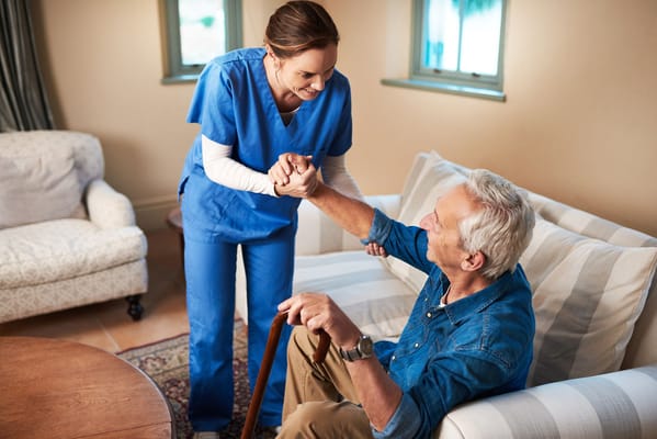 A caregiver assisting a senior man in a comfortable room