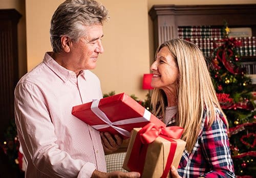 Two residents exchanging gifts in a festive interior