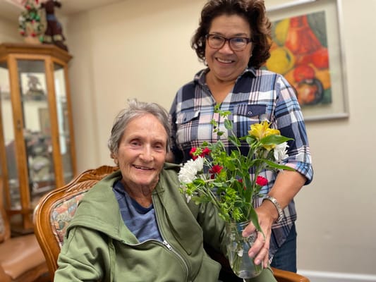 Resident and staff member smiling together with flowers