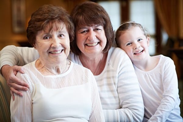 Three generations smiling together in a common area