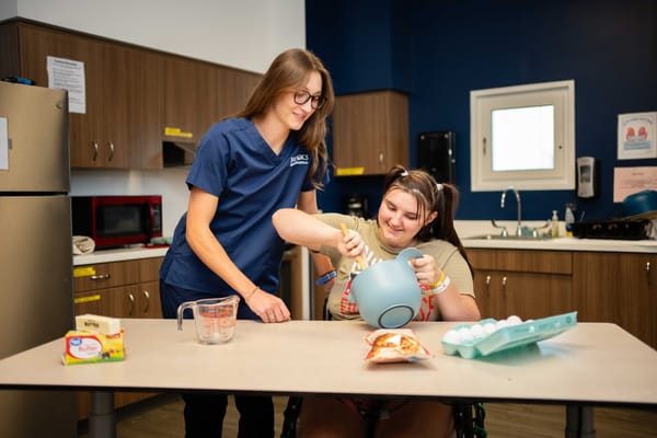 Staff assisting a resident with an activity in a kitchen