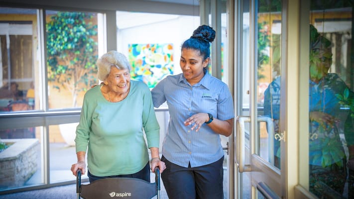 Resident and staff member walking together in a hallway