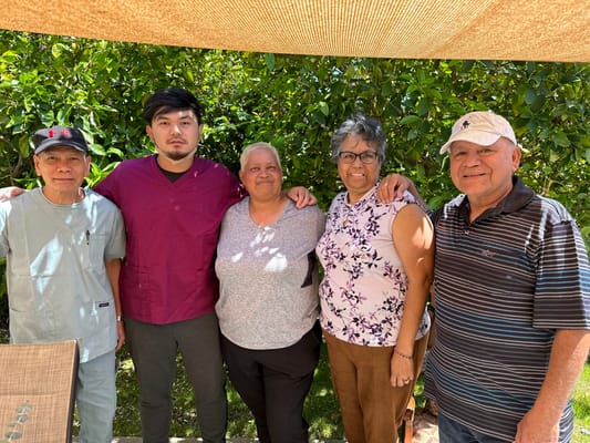 Residents and staff posing together in a garden setting