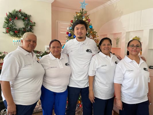 Staff members posing in front of a decorated Christmas tree