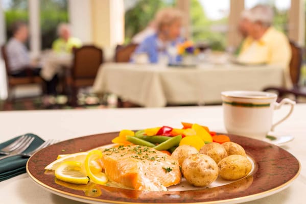A beautifully plated meal with residents enjoying a dining experience in the background