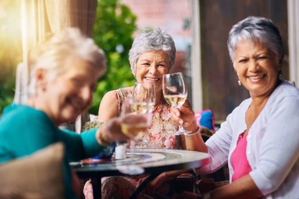 Three residents toasting with drinks outdoors