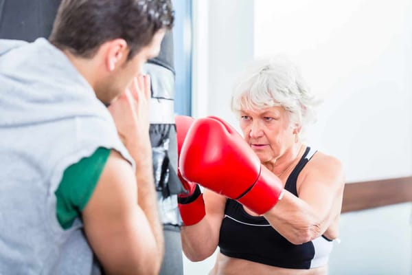 Senior woman boxing with a trainer in a fitness session