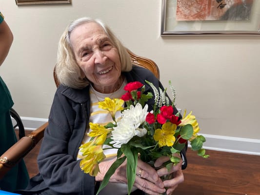 Resident smiling while holding a bouquet of flowers