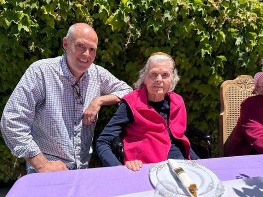 Resident enjoying a sunny outdoor gathering with staff member