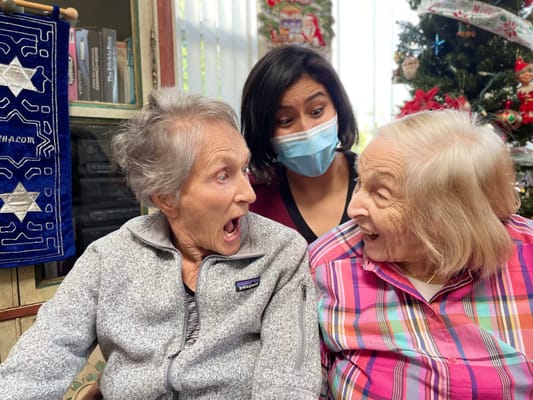 Two residents laughing with staff during a holiday celebration