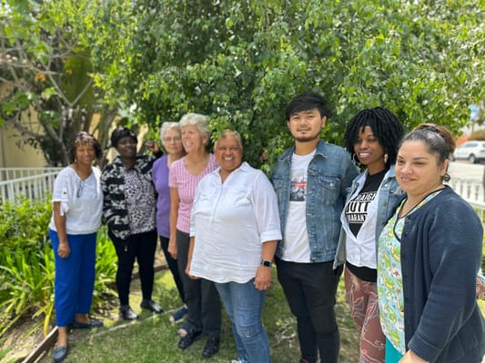 Staff members posing together outdoors in a garden area