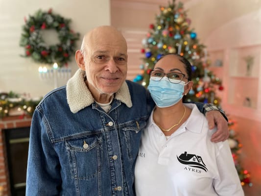 A resident and staff member smiling by a festive tree