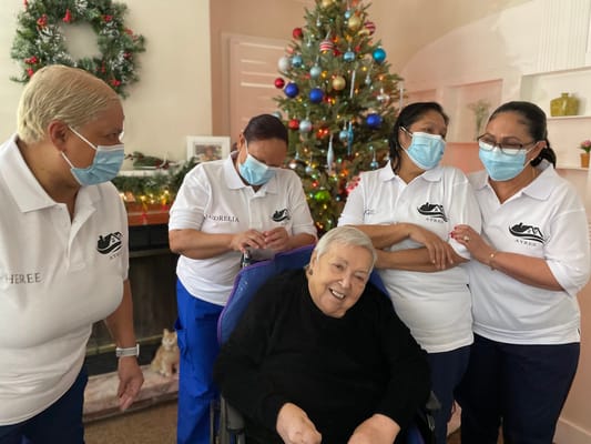 Residents and staff celebrating together near a decorated Christmas tree