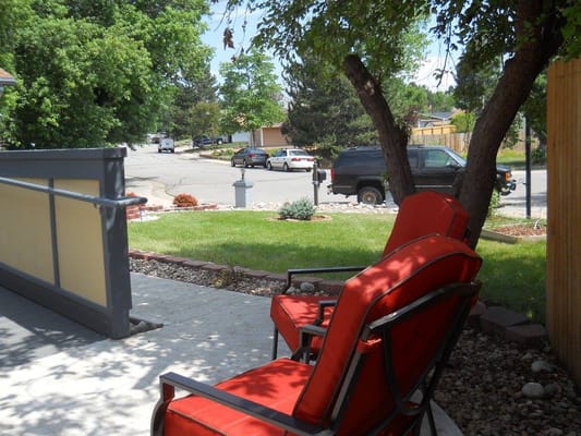 Outdoor seating area with red chairs and green lawn