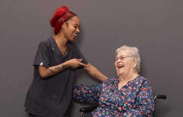 Caregiver laughing with a resident in a common area