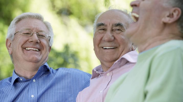 Three senior men laughing together outdoors