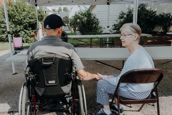 Residents holding hands under a canopy tent