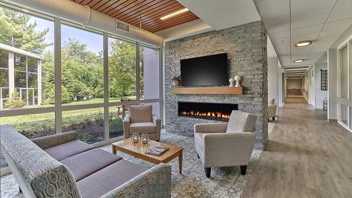 Bright common area with seating and windows overlooking a garden