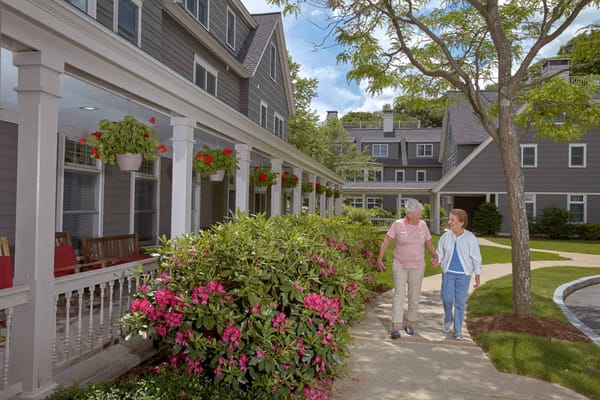 Two women walking along a garden path outside the facility