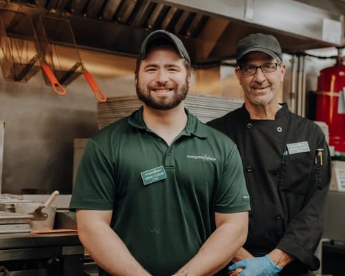 Two staff members smiling in the kitchen