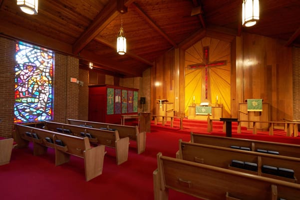 Interior view of a chapel with wooden pews and stained glass