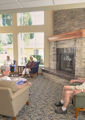 Residents socializing in a cozy common area by the fireplace.