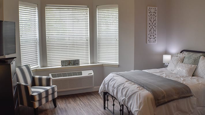 Brightly decorated private resident room with a bed and chair