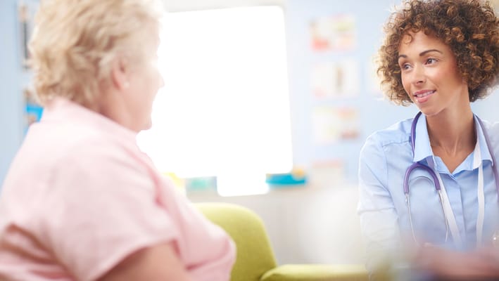A staff member talking with a resident in a bright room