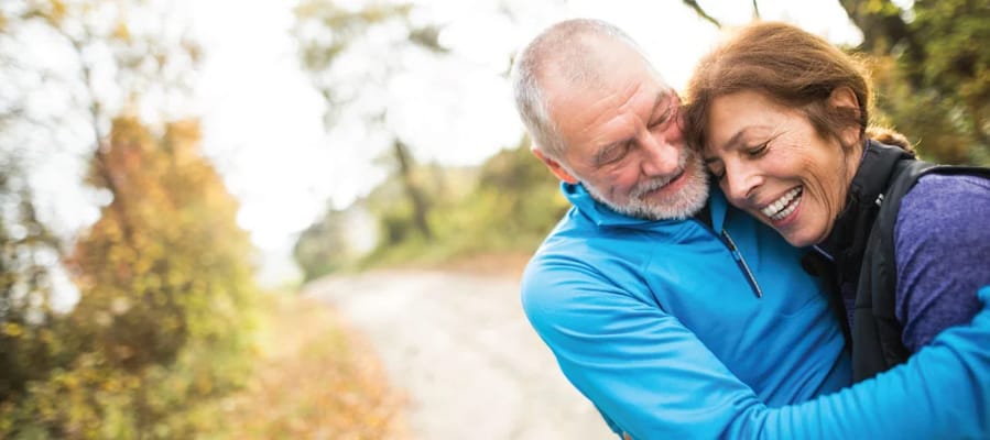 Two seniors joyfully embracing outdoors in a natural setting
