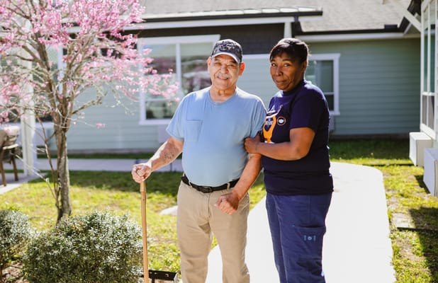 A staff member holds hands with a resident outdoors