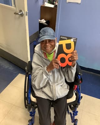 Resident in a wheelchair holding a magazine in a common area
