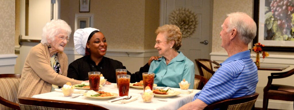 Residents and staff enjoying a meal together in the dining room
