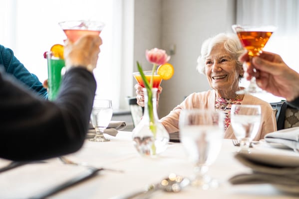 Residents toasting with drinks at a dining table