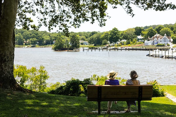 Two residents sitting on a bench by the water